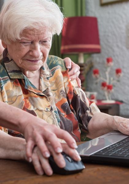 Oudere vrouw aan computer krijgt hulpt